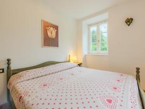 a bedroom with a bed with a bedspread and a window at Apartment Abete e Betulla by Interhome in Rabbi