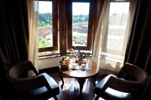 a table and two chairs in a room with two windows at The Treetops Lodge in Nyeri +24 photos