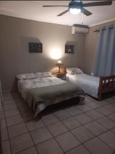 a bedroom with two beds and a ceiling fan at Ligema Lodge in Malelane