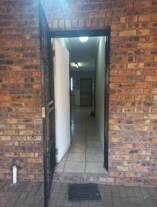a brick wall with an open door into a hallway at Ligema Lodge in Malelane