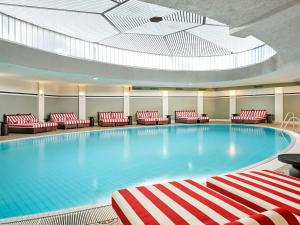 a large swimming pool with red and white chairs at Bristol Berlin, Vignette Collection by IHG in Berlin