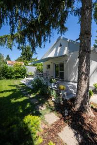 a white house with a tree in the yard at Világos Kert Oliva House Steam in Balatonvilágos