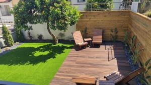 a backyard with a wooden deck with chairs and grass at DiROMANE in Braga