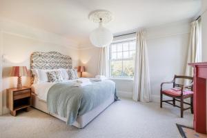 a bedroom with a bed and a chair and a window at Sandown, Spacious and Stylish in Southwold in Southwold