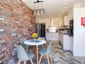 a kitchen with a brick wall and a table and chairs at Ty Haul in Rhosneigr