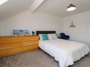 a bedroom with a large bed and a wooden dresser at Ty Haul in Rhosneigr