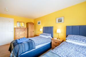 two beds in a room with yellow walls at 2 Bed in Bamburgh oc-nb282 in Bamburgh