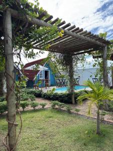 a wooden pergola in a yard with a house at Chalé Entre Ciclos Icaraizinho in Amontada
