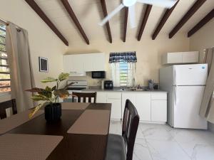 a kitchen with a table and a white refrigerator at Villadeco Escape, Gated Cottage with Generator in West End