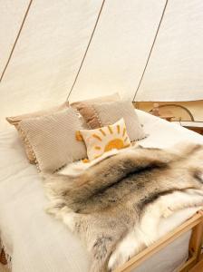 a bed with a furry blanket and pillows on it at LaplandLiv Glampingtent with private sauna at the lake! in Mellanström +39 photos