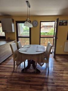 a dining room table with chairs and a clock on the wall at Apartmán Ružiná in Ružiná