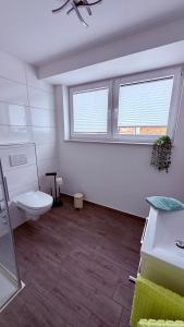 a bathroom with a toilet and two windows at Ferienwohnung im Ellertal in Bockelnhagen