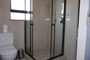 a bathroom with a glass shower with a toilet at The Ulysses Motel in Ga-Mothiba +42 photos