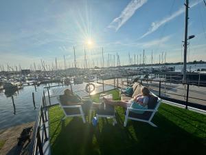 two people sitting in chairs on a dock with a marina at Luxury Houseboat Wolphaartsdijk VP109 in Wolphaartsdijk