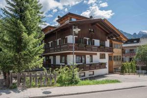 a large wooden house with a fence in front of it at Alpen Suite Apartment in San Vigilio Di Marebbe