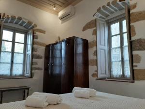 ein Schlafzimmer mit einem Holzschrank und zwei Fenstern in der Unterkunft En Patmo Holiday Home in Patmos