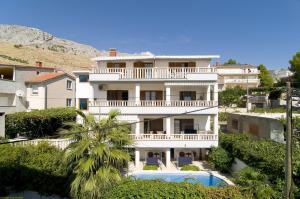 a large white house with a balcony and a swimming pool at Dizma Welness Apartmani in Duće