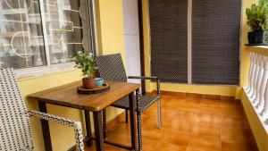 a small table and chairs on a balcony with a window at Shelter Guest House in Candolim