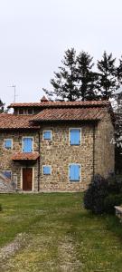 a stone house with blue windows in a yard at Country Hill B&B in Arezzo