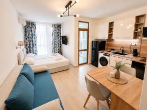 a living room with a blue couch and a kitchen at AM Sea Studios in Ravda
