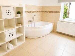 a white bathroom with a tub and a window at Pokoje nad Welem Lidzbark in Lidzbark +22 photos