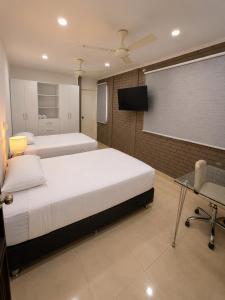 a bedroom with two beds and a tv and a desk at Hotel Luna Del Rio in Puerto Salgar