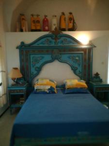 a bedroom with a blue bed with two pillows at Villa De la mer in Rafrāf
