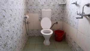 a bathroom with a toilet and a red bucket at Shelter Guest House in Candolim