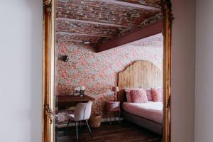 a mirror in a bedroom with a bed and a desk at Casa Cava B&B in Dendermonde