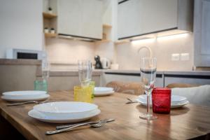 a wooden table with plates and wine glasses on it at Sweet Memories-Gravedona 100m to Lake-Lake Como Escape in Gravedona +25 photos