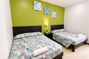 due letti in una stanza con pareti verdi di Hotel Plazha Express a Tuxtla Gutiérrez Altre 17 foto