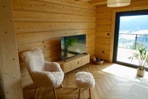 a living room with wooden walls and a tv and two chairs at Chaty Korňa in Predmerská