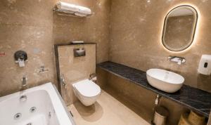 a bathroom with a sink and a toilet and a mirror at Fun Hotels Gandhinagar in Gandhinagar
