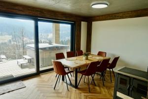 a dining room with a table and chairs and a large window at Chaty Korňa in Predmerská