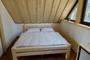 a bed in a small room with a wooden ceiling at Chaty Korňa in Predmerská