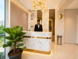 a man in a suit standing behind a counter in a lobby at Fun Hotels Gandhinagar in Gandhinagar