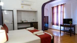 a bedroom with a bed and a television in it at Shelter Guest House in Candolim