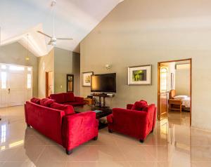a living room with red furniture and a tv at Hispaniola Residential - Villas & Apartments! in Sosúa