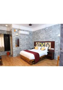 a bedroom with a bed and a stone wall at Anbu Grand Inn in Chidambaram