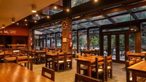 a restaurant with wooden tables and chairs and windows at Andina Principal in Machu Picchu
