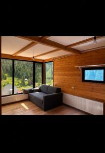 a living room with a couch in a room with windows at Bakhmaro Eco Cottage in Chʼkhakoura