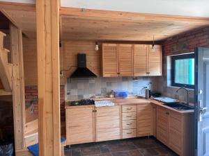 a kitchen with wooden cabinets and a stove at Bakhmaro Eco Cottage in Chʼkhakoura