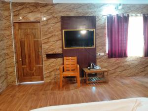 a room with a television and a chair and a door at Anbu Grand Inn in Chidambaram