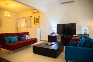 a living room with two red couches and a flat screen tv at Résidence Touraco in Abidjan