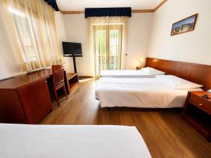 a hotel room with two beds and a television at Hotel International in Tarvisio