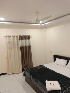 a bedroom with a bed and a ceiling fan at Hotel Bhagwati Palace in Ujjain