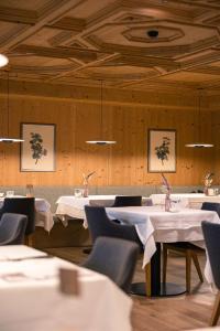 a dining room with white tables and chairs at Granpanorama Hotel StephansHof in Villandro