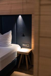 a bedroom with a bed and a nightstand with a lamp at Granpanorama Hotel StephansHof in Villandro