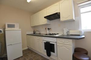 Una cocina con gabinetes blancos y un horno de estufa. en Skiddaw Grove, en Keswick