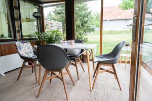 ein Tisch und Stühle in einem Zimmer mit Fenstern in der Unterkunft Ferienhaus WaldPeter bei CaroGrün in Erfurt-gemütlich-sonnig-Garten-Parken-Pool-Sauna-WLAN in Erfurt